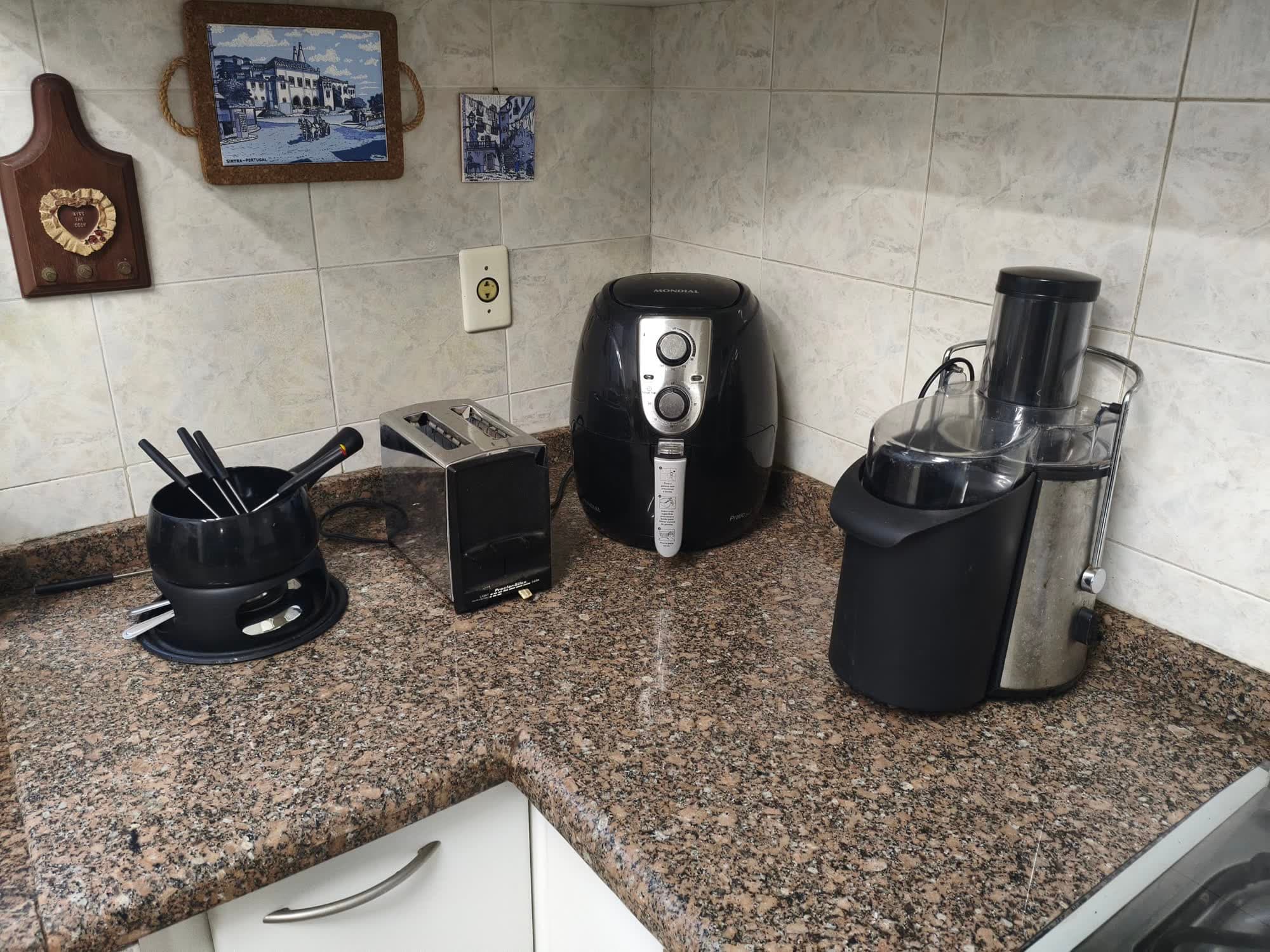 A bancada da cozinha com o aparelho de fondue, a torradeira, a airfryer e a centrífuga