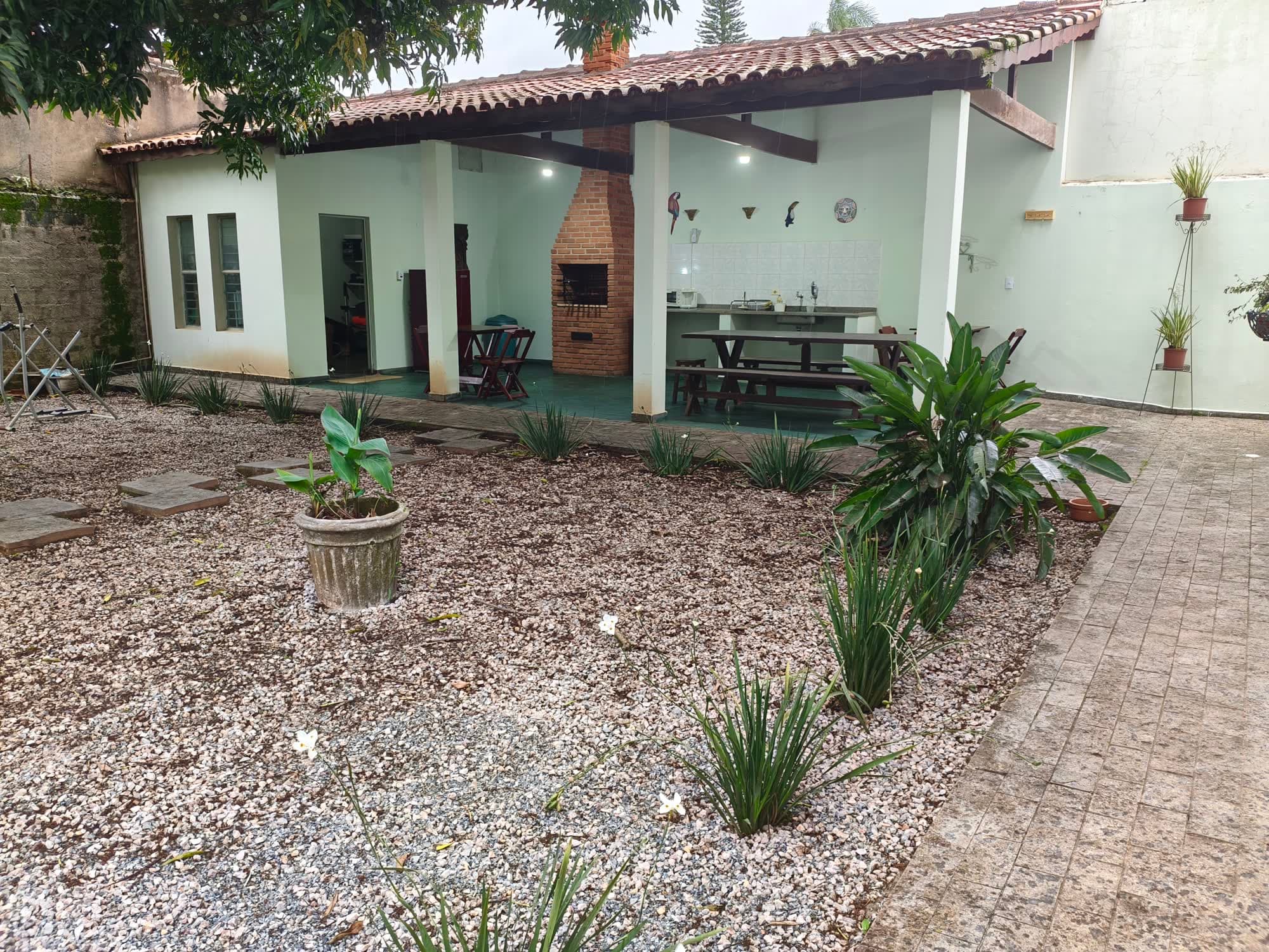 O jardim de pedrinhas brancas junto ao muro do terreno, com a área gourmet ao fundo