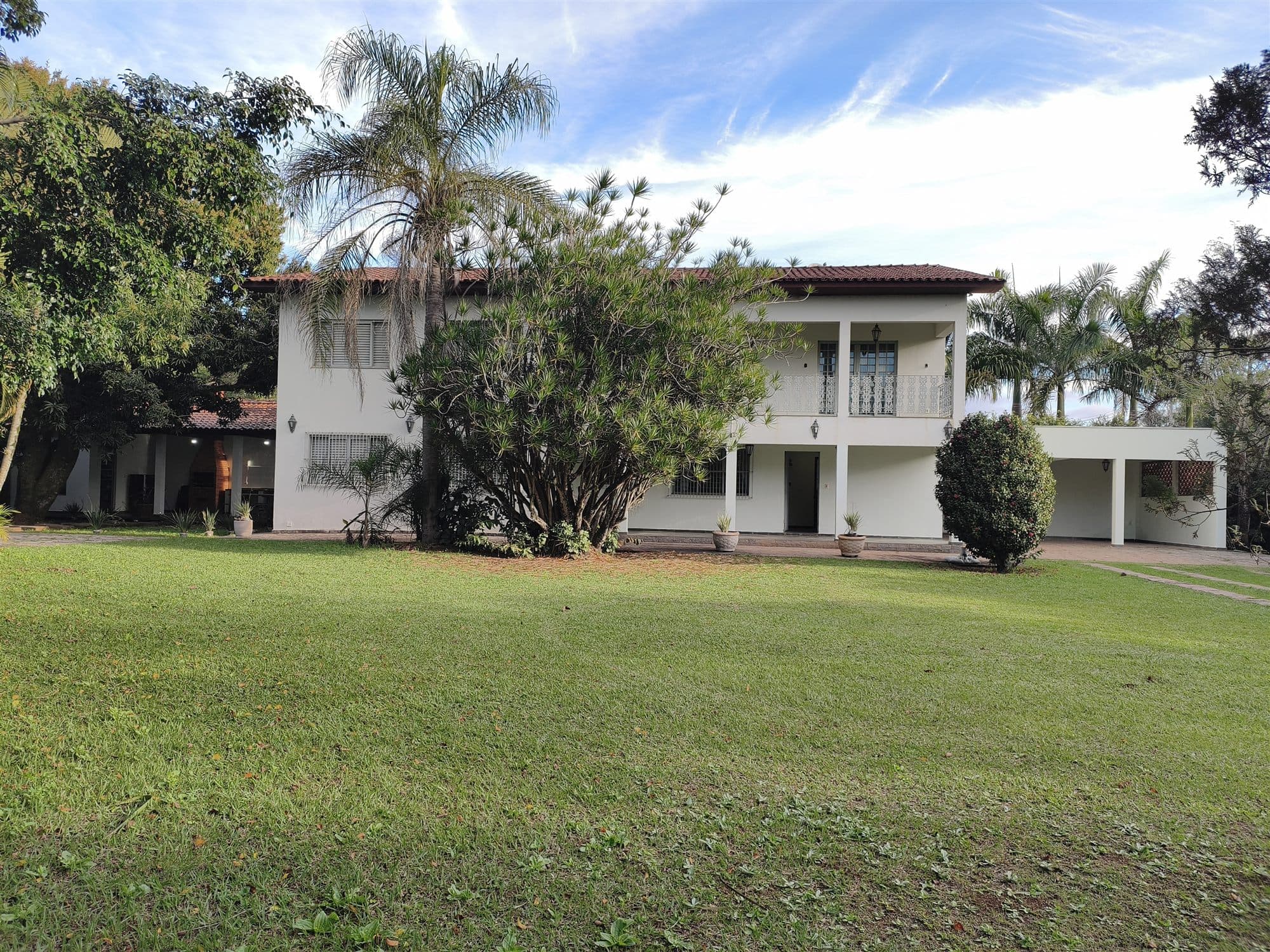 A fachada inteira vista do jardim, com a varanda coberta no pavimento superior