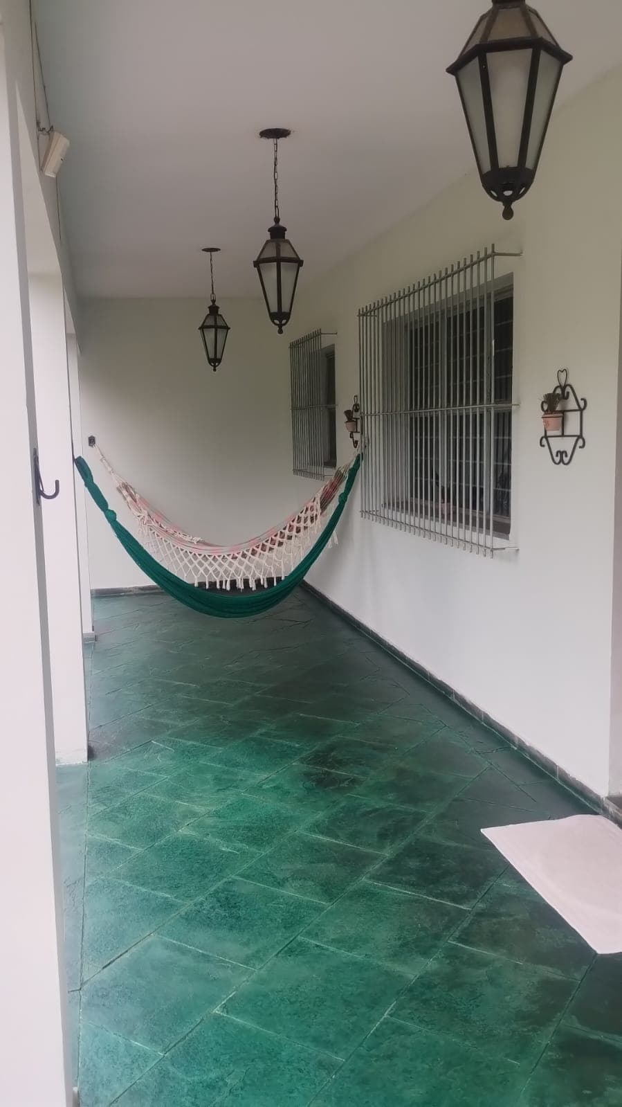 A varanda de baixo com redes de descanso armadas e o piso verde polido