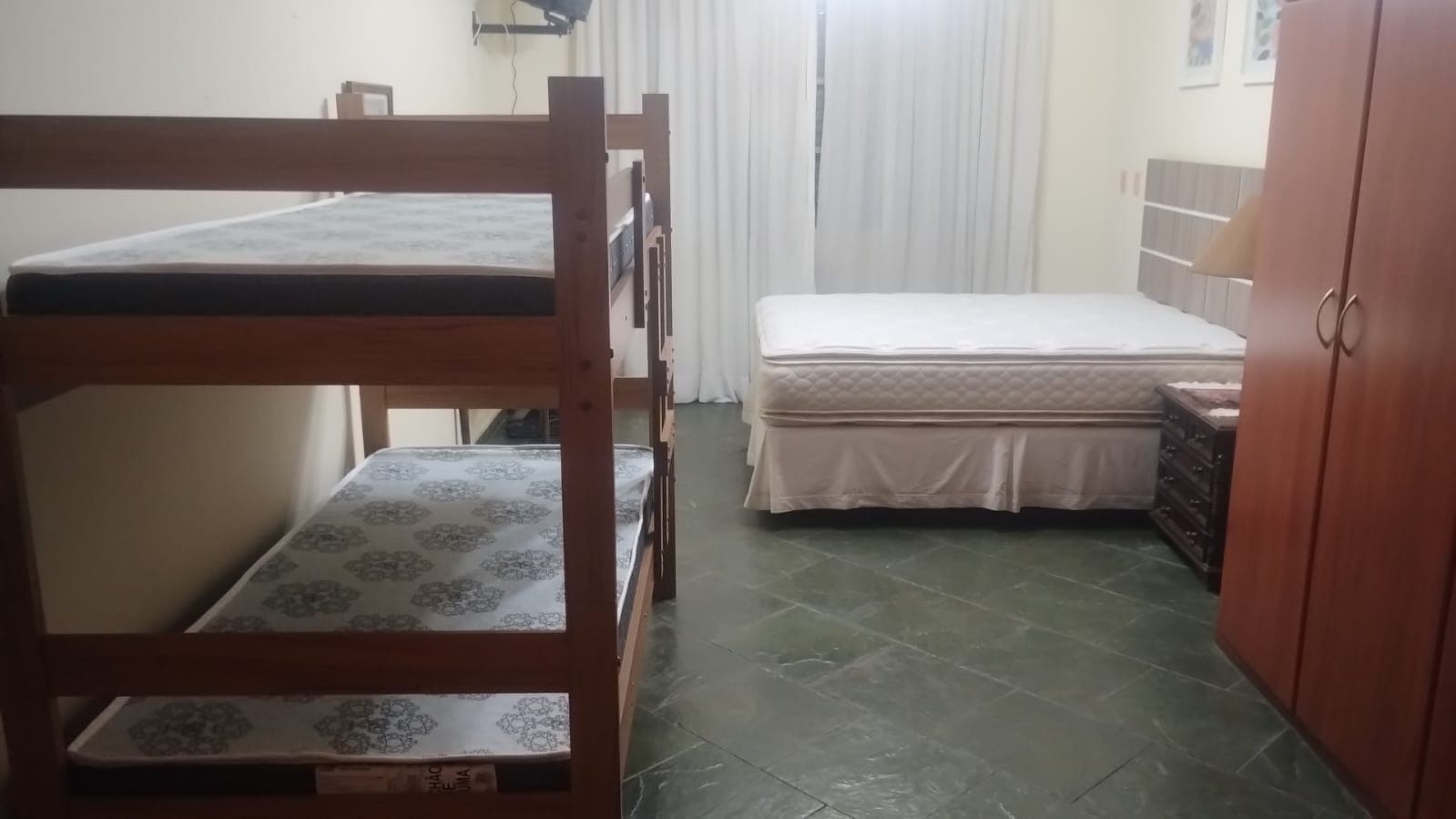 O quarto com beliche e cama de casal, cortinas novas e armário embutido